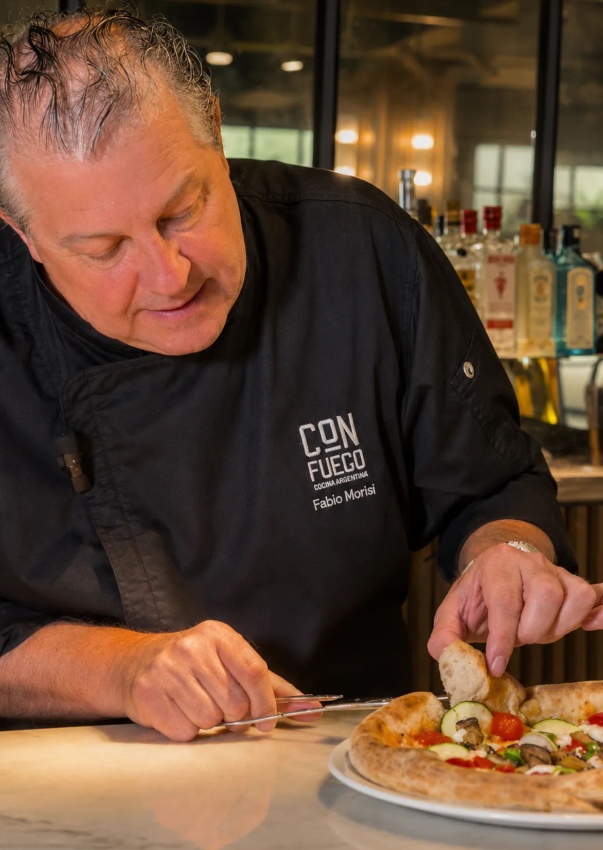 El chef Fabio Morisi terminando una pizza de verduras en la cocina del restaurante ÔVEN